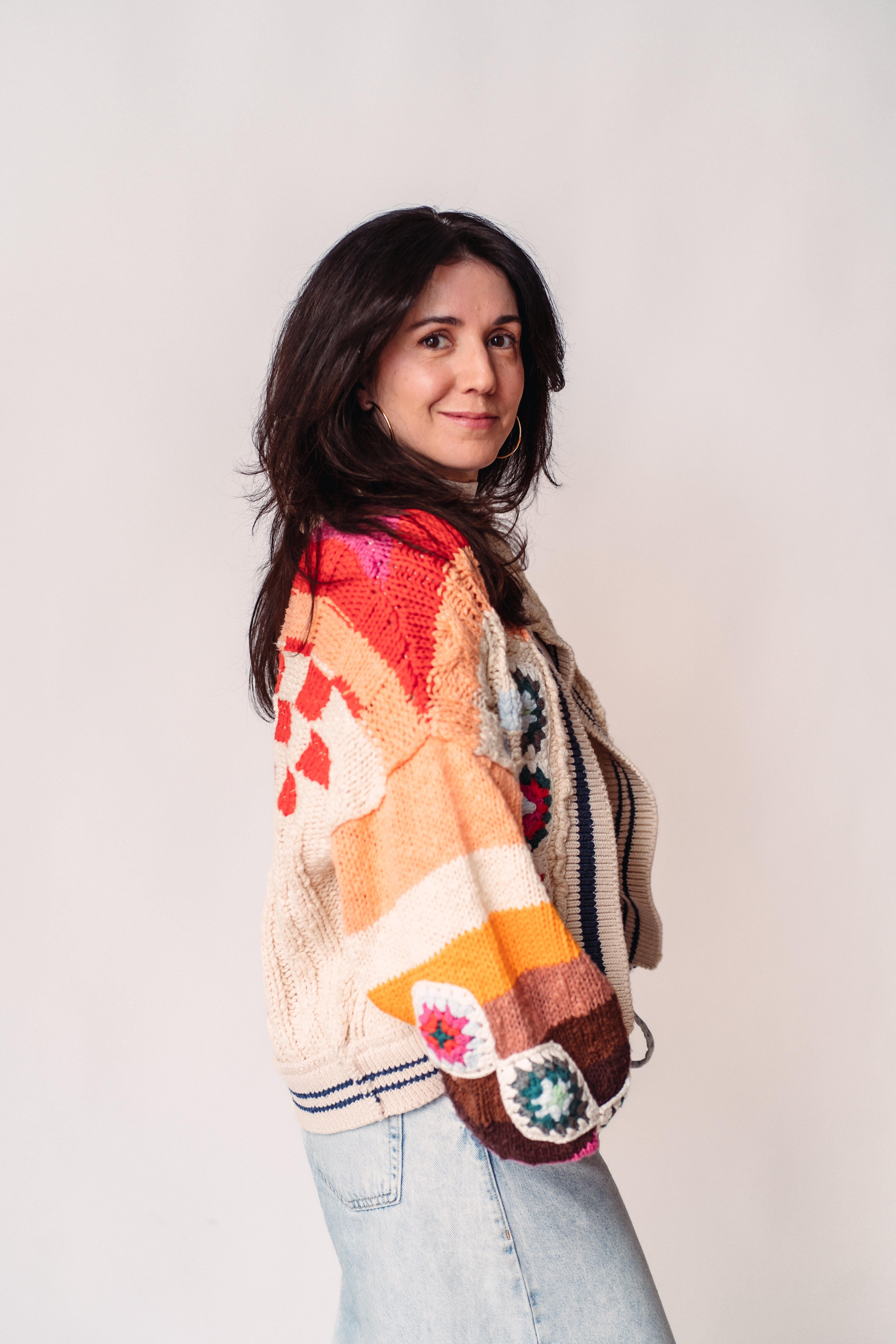 Kate O'Grady wearing a colorful patchwork cardigan against a plain background